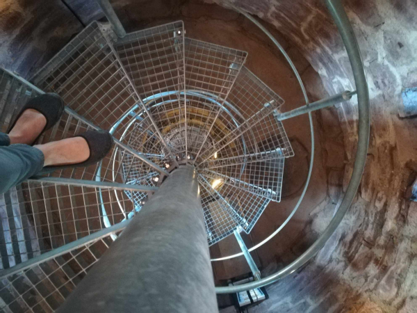 Metallene Wendeltreppe, die nach unten führt, jemand steht auf der oberen Stufe.