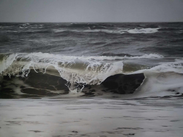 Kippende Nordseewelle vor grauem Himmel