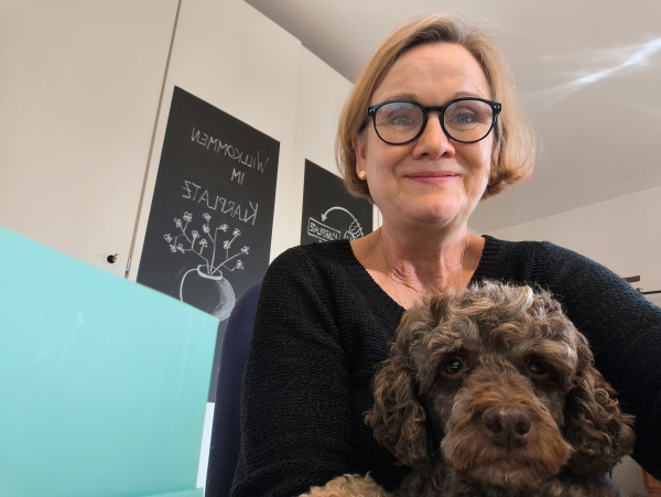 Claudia Stellmacher-Köthe im Büro mit braunem Pudel auf dem Schoß